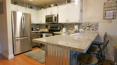 Kitchen featuring white cabinets, kitchen peninsula, appliances with stainless steel finishes, and tasteful backsplash | Image 3