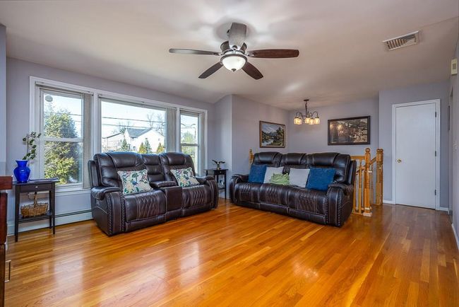 Living room featuring hardwood finished floors, ceiling fan with notable chandelier | Image 9