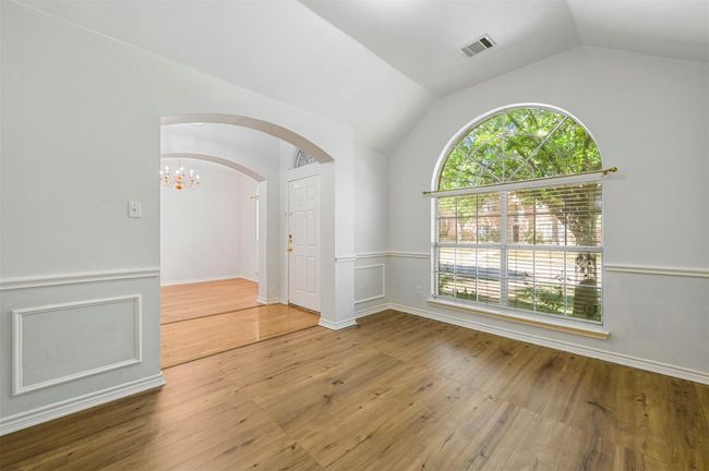 Unfurnished room with arched walkways, lofted ceiling, a chandelier, and wood-type flooring | Image 19