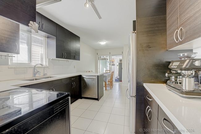 Kitchen featuring light tile patterned floors, tasteful backsplash, a sink, stainless steel appliances, and light countertops | Image 5