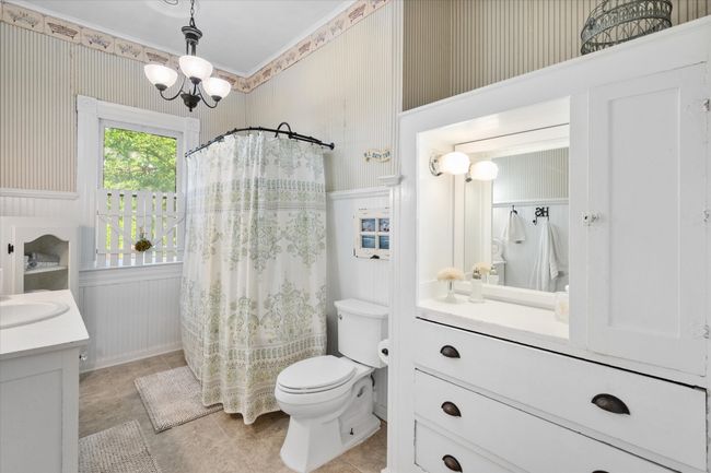 Full bathroom featuring vanity, toilet, wainscoting, a chandelier, and wallpapered walls | Image 26