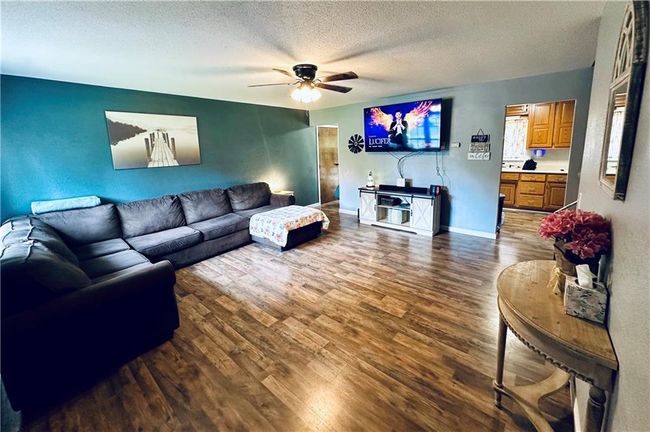 Living area with a ceiling fan, dark wood-style floors, a textured ceiling, and baseboards | Image 5