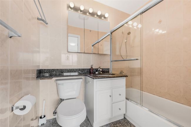 Bathroom with tile walls, vanity, and bath / shower combo with glass door | Image 22