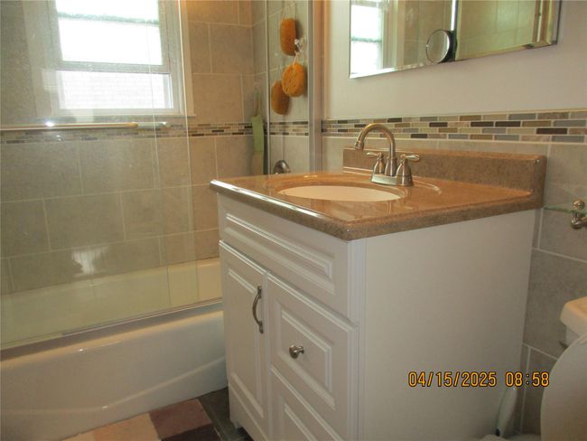 Bathroom with shower / bath combination with glass door, vanity, tile walls, and toilet | Image 12