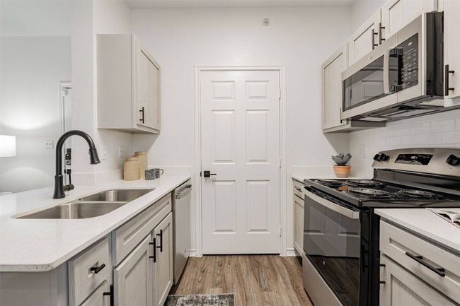 Kitchen with backsplash, sink, stainless steel appliances, and light hardwood / wood-style flooring | Image 19