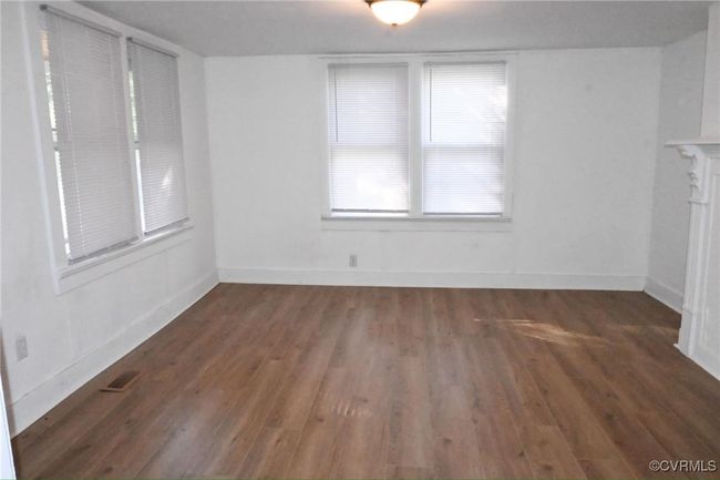 Unfurnished living room with wood finished floors, baseboards, and visible vents | Image 11