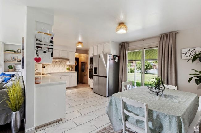 Kitchen featuring appliances with stainless steel finishes, white cabinets, light countertops, decorative backsplash, and light marble finish floors | Image 6