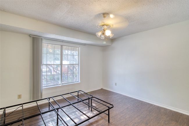 Empty room with wood finished floors, a ceiling fan, and a textured ceiling | Image 4