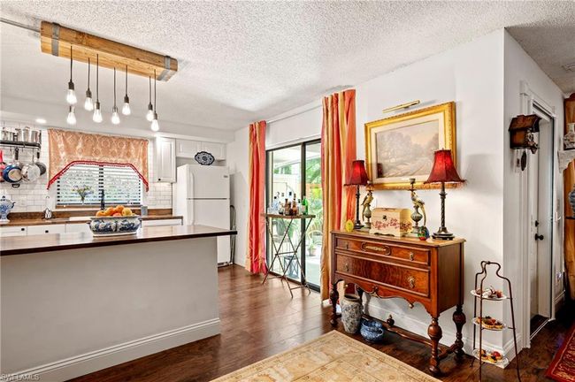 Kitchen featuring dark countertops, dark wood finished floors, freestanding refrigerator, tasteful backsplash, and a textured ceiling | Image 16