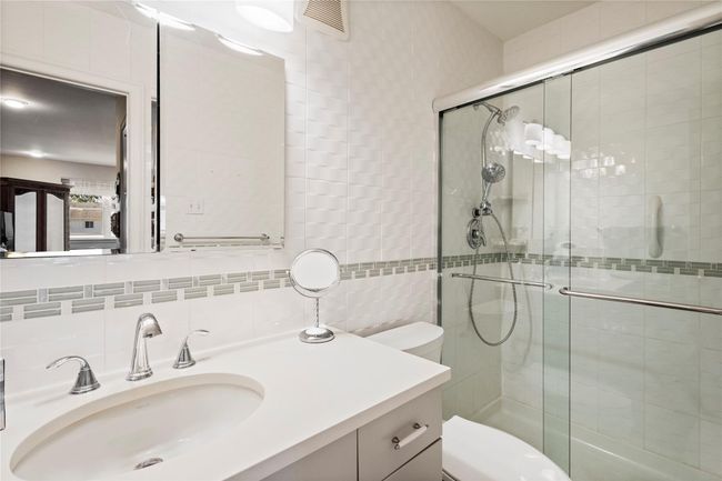 Bathroom featuring tile walls, toilet, a stall shower, vanity, and tasteful backsplash | Image 24