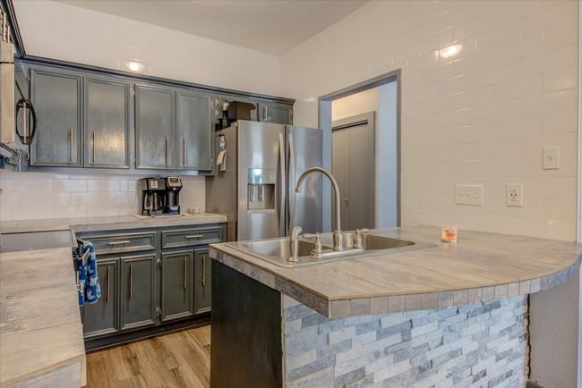 Kitchen featuring stainless steel appliances, a peninsula, light wood-style floors, light countertops, and backsplash | Image 7