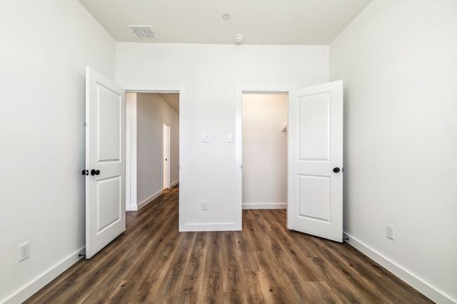 Unfurnished bedroom featuring dark wood-style flooring, baseboards, and a walk in closet | Image 26