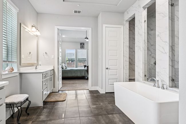 Ensuite bathroom featuring a freestanding bath, vanity, a ceiling fan, and a marble finish shower | Image 18