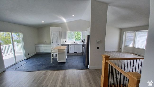 Kitchen featuring lofted ceiling, white cabinetry, a center island, appliances with stainless steel finishes, and a kitchen bar | Image 7