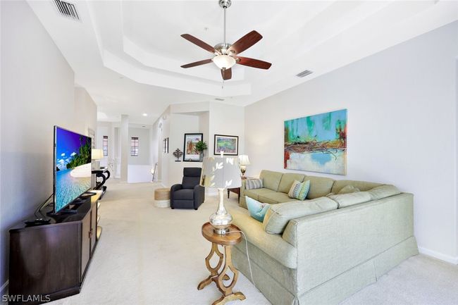 Carpeted living room featuring ceiling fan and a tray ceiling | Image 9