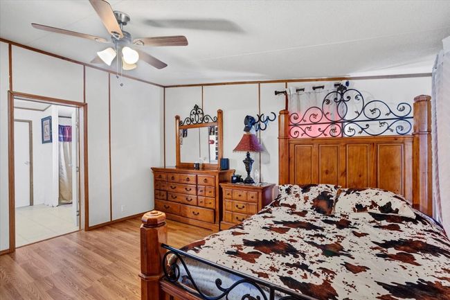 Bedroom with ornamental molding, light wood-style flooring, and a ceiling fan | Image 14