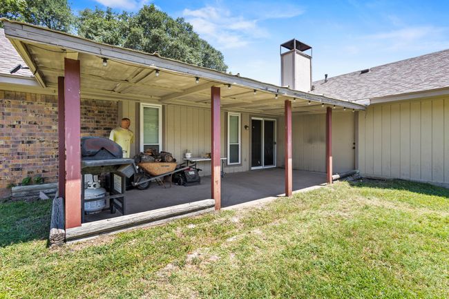 Back of house featuring a chimney, a lawn, a patio area, roof with shingles, and brick siding | Image 23
