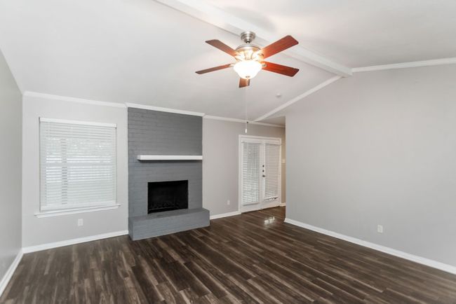 Unfurnished living room with a brick fireplace, wood finished floors, and ceiling fan | Image 5