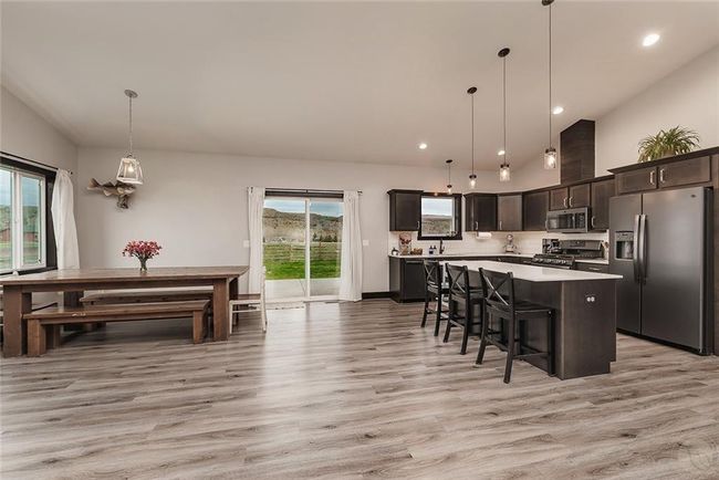 Kitchen with elegant quartz counter tops, pendant and under counter lighting LVP flooring thruout the Great room. SS appliances, direct vent ffan over gas range. Sliding glass patio doors to the back yard. | Image 7