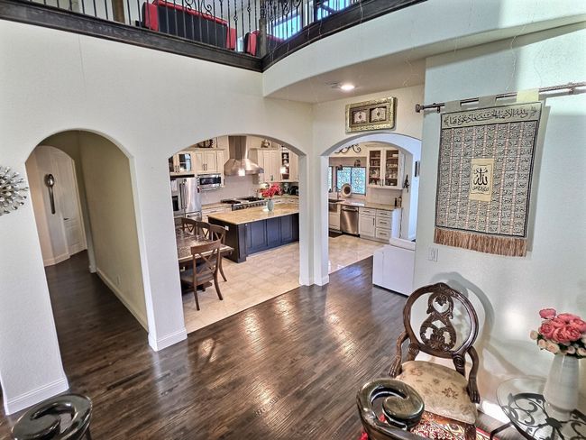 Foyer entrance with arched walkways, dark wood-type flooring, a high ceiling, and baseboards | Image 21