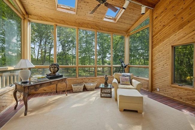 Sunroom featuring healthy amount of natural light, a skylight, lofted ceiling, and ceiling fan | Image 4