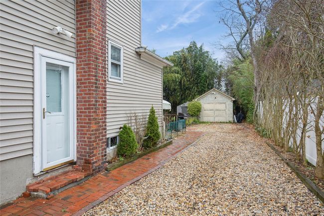 View of home's exterior featuring a detached garage, an outdoor structure, entry steps, fence, and gravel driveway | Image 25