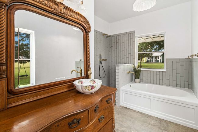 Bathroom with vanity, a bath, a tile shower, and unfinished concrete flooring | Image 15