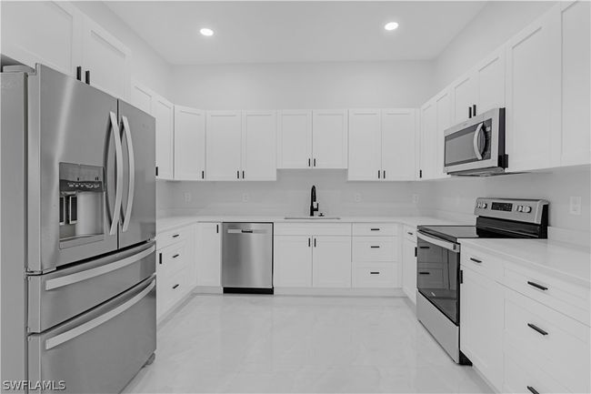 Kitchen with white cabinetry, sink, light tile floors, and stainless steel appliances | Image 31