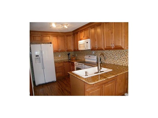 Kitchen featuring white appliances, a sink, brown cabinets, and backsplash | Image 11