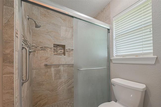 Primary bath features a Upgraded walk-in shower with custom tile and large window for natural lighting | Image 16