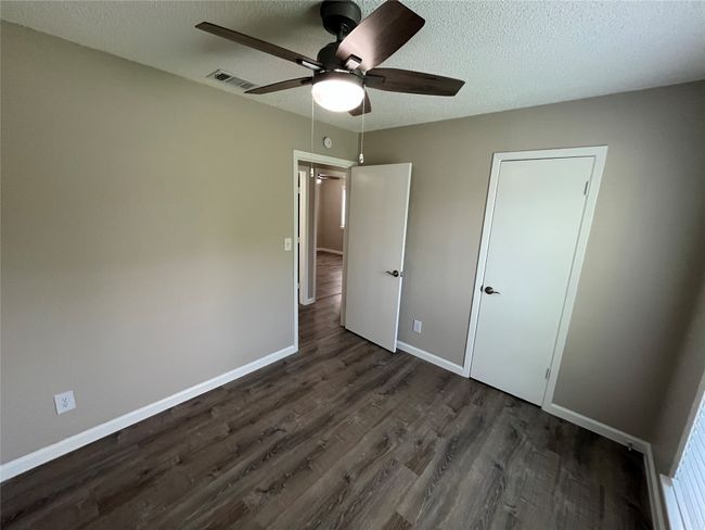 Unfurnished bedroom with dark wood-type flooring, baseboards, a textured ceiling, and a ceiling fan | Image 17