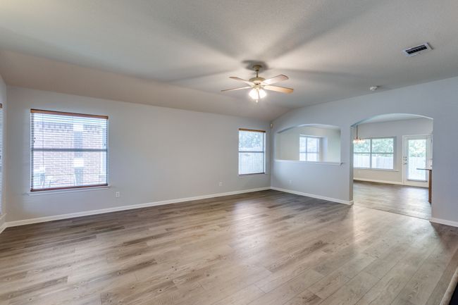 Empty room featuring ceiling fan, arched walkways, and wood finished floors | Image 6