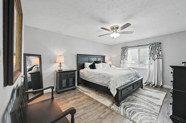 Bedroom featuring light wood-type flooring, a ceiling fan, and a textured ceiling | Image 24