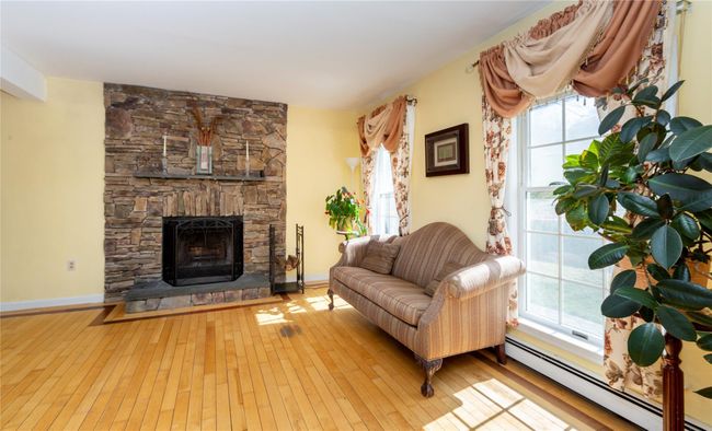 Living room featuring hardwood / wood-style floors, a baseboard heating unit, and a fireplace | Image 20