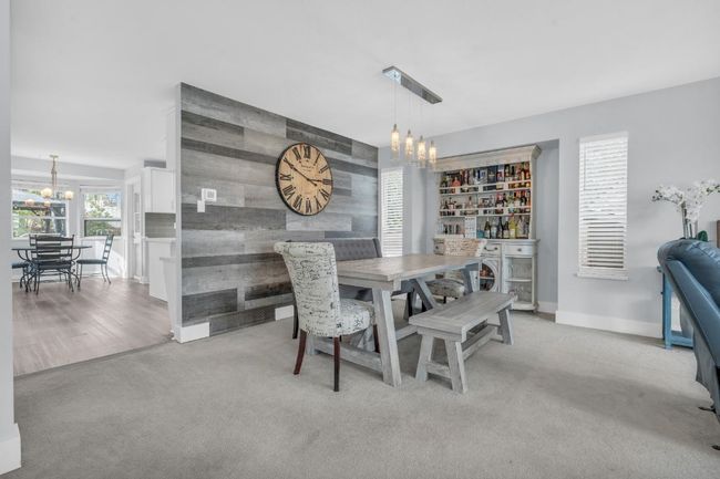 Dining area featuring an accent wall, an inviting chandelier, light colored carpet, and baseboards | Image 6