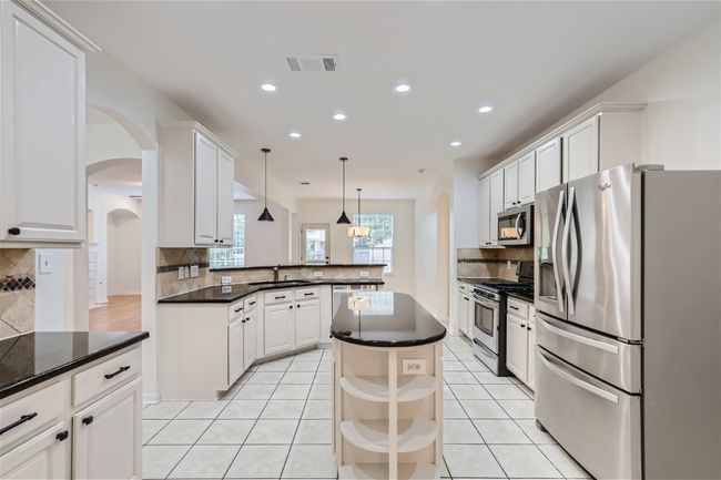 Kitchen with stainless steel appliances, a sink, backsplash, a peninsula, and recessed lighting | Image 8