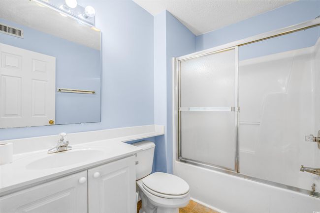 Full bath featuring vanity, shower / bath combination with glass door, a textured ceiling, and tile patterned floors | Image 19