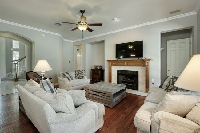 Living area with visible vents, a ceiling fan, ornamental molding, arched walkways, and a premium fireplace | Image 8
