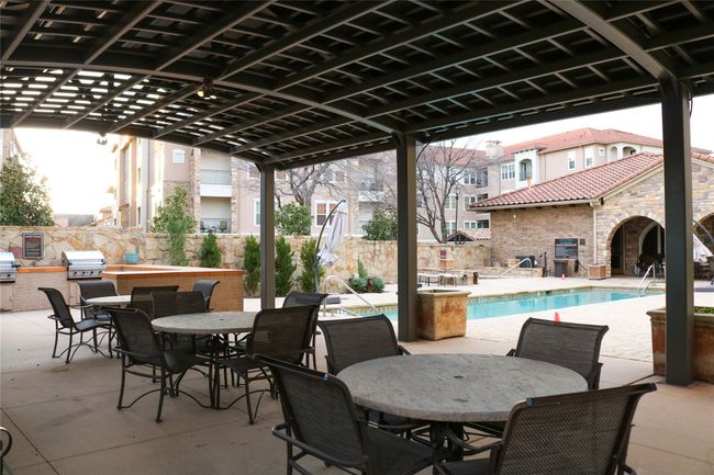 View of patio / terrace featuring area for grilling, a grill, a community pool, fence, and outdoor dining area | Image 32