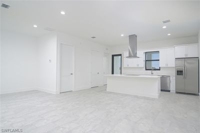 Kitchen with white cabinets, appliances with stainless steel finishes, fume extractor, and light tile flooring | Image 3