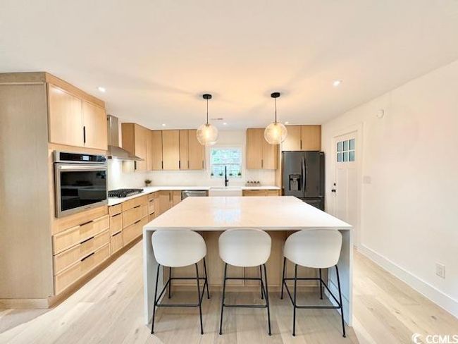 Kitchen with appliances with stainless steel finishes, light brown cabinets, wall chimney exhaust hood, light wood-style flooring, and recessed lighting | Image 9