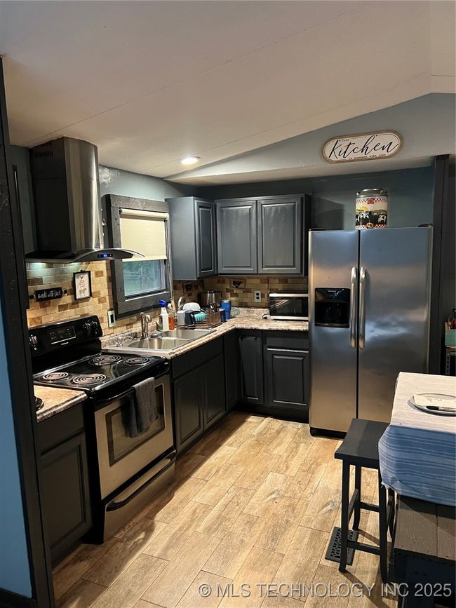 Kitchen featuring range, extractor fan, refrigerator, light wood-style floors, and decorative backsplash | Image 7