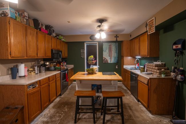Kitchen featuring appliances with stainless steel finishes, a sink, ceiling fan, light countertops, and brown cabinetry | Image 9