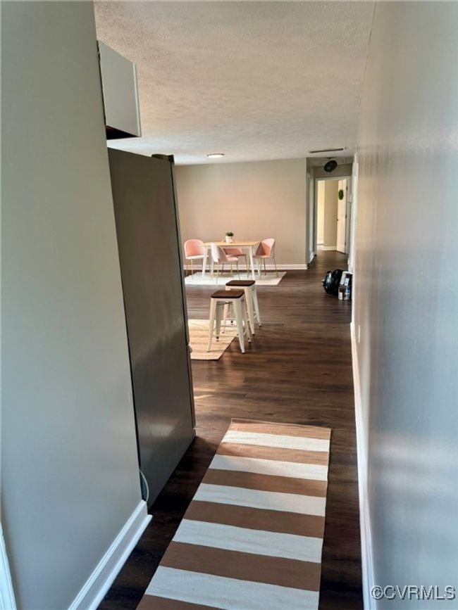 Corridor with a textured ceiling, baseboards, and dark wood-style flooring | Image 19