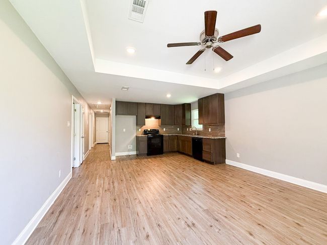 Kitchen featuring light wood-type flooring, a raised ceiling, black appliances, recessed lighting, and light countertops | Image 10