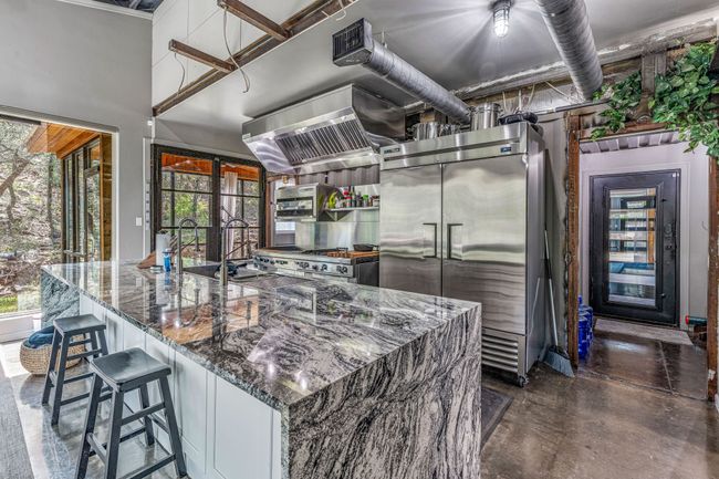 Kitchen with wall chimney exhaust hood, stainless steel built in refrigerator, finished concrete floors, and a healthy amount of sunlight | Image 15