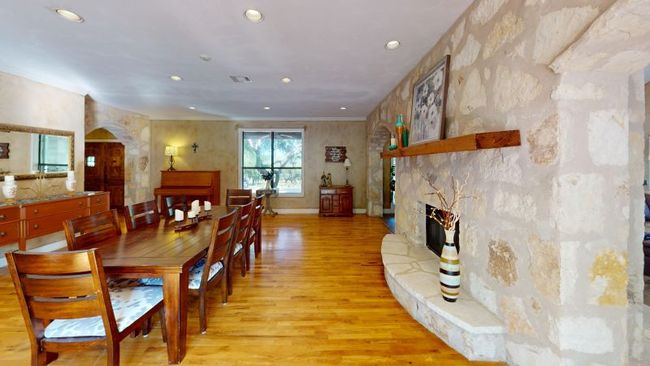 Dining area with wood flooring, arched rock walkways, recessed lighting, a fireplace, and baseboards | Image 10