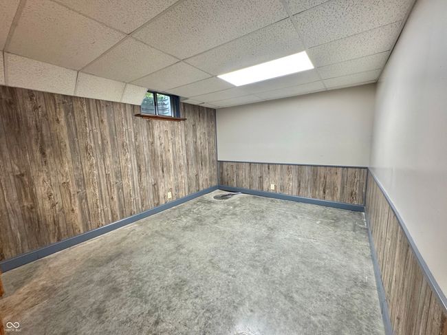 carpeted spare room with wooden walls, a drop ceiling, and wainscoting | Image 65