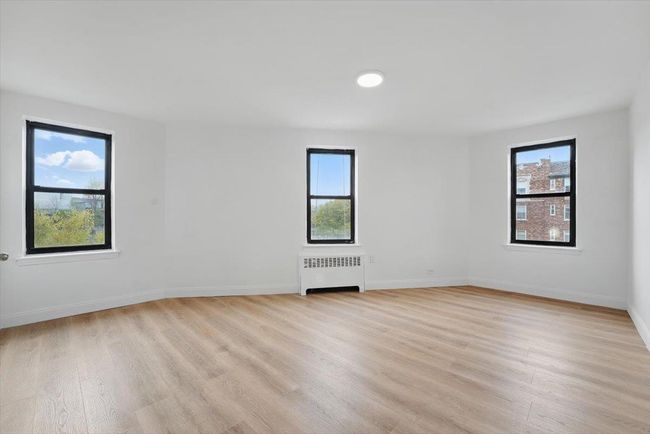 Empty room featuring radiator, light wood-style flooring, and a healthy amount of sunlight | Image 14