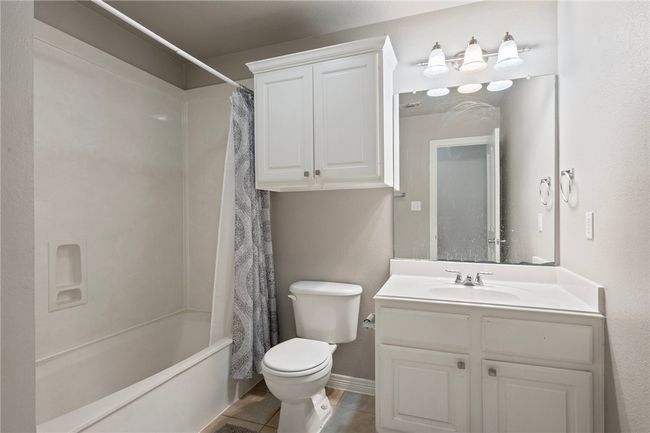 Bathroom with toilet, vanity, shower / bathtub combination with curtain, and tile patterned flooring | Image 9